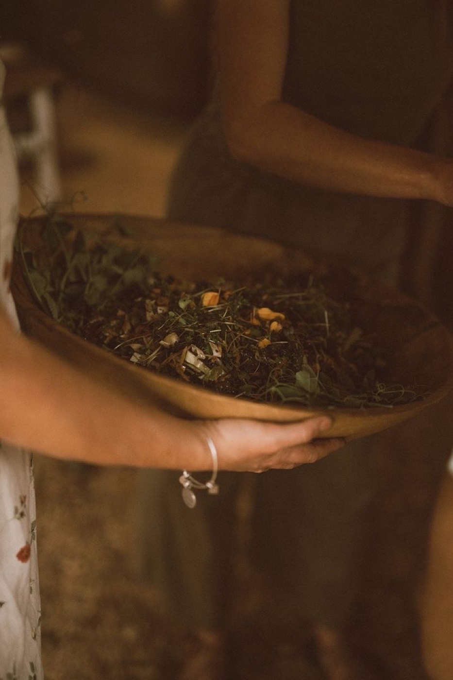 A wooden bowl of herbs and flowers
